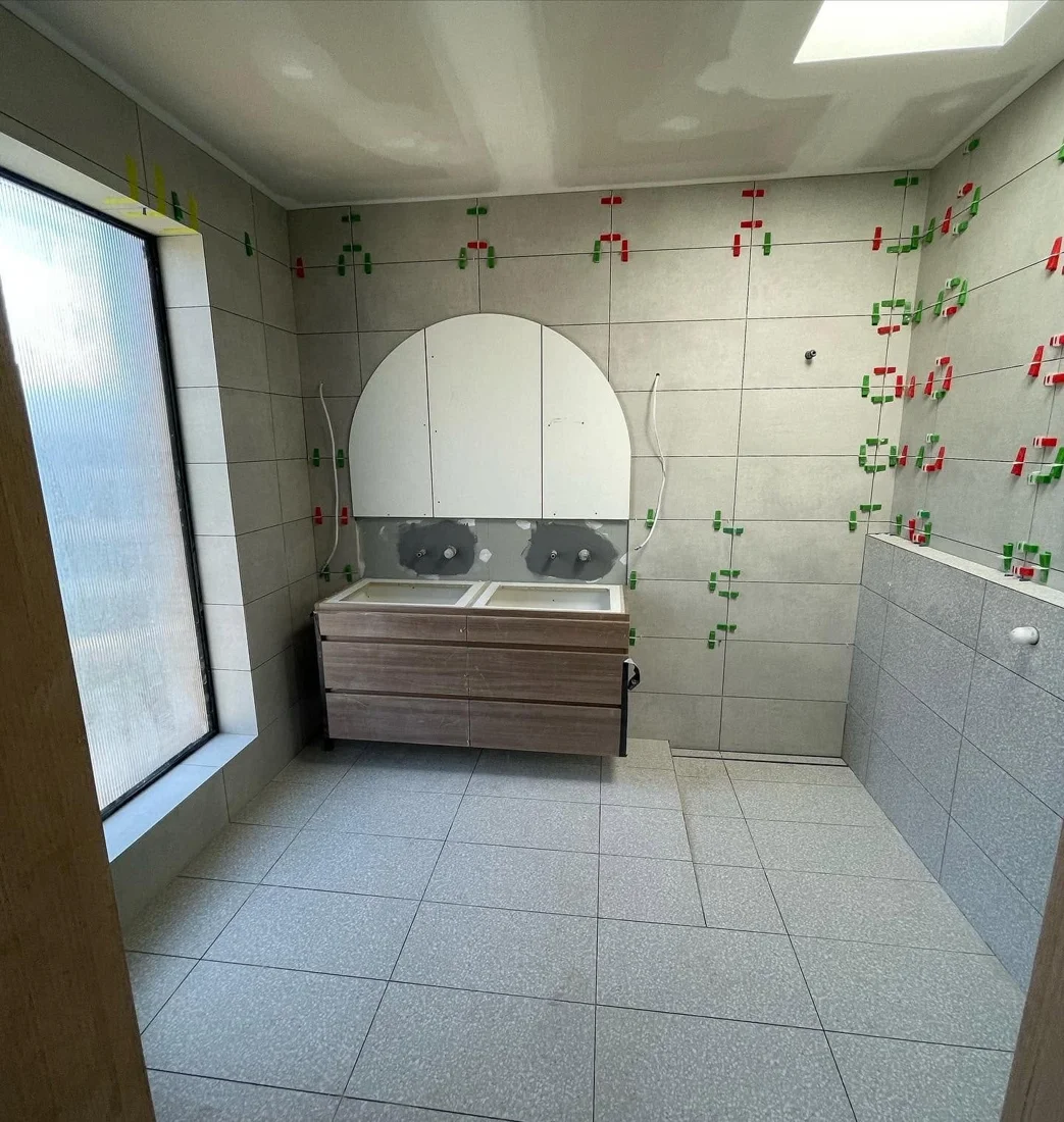 Bathroom renovation in progress, showing wall preparation and floor tiling