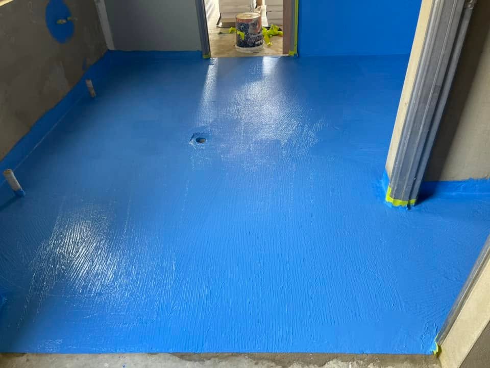 Blue waterproofing membrane applied to a wet-area floor and wall bases